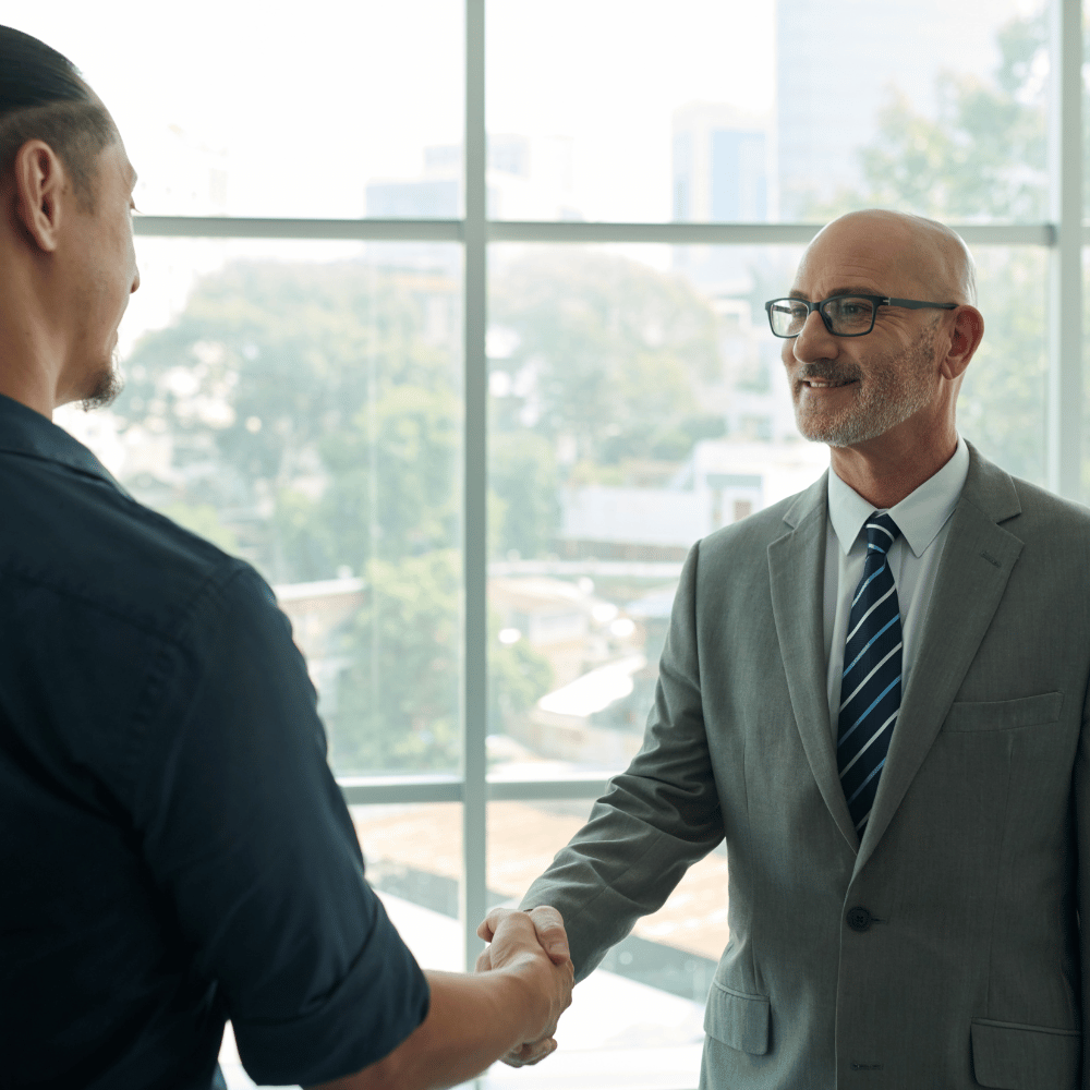 Zwei Personen reichen sich im Büro die Hand als Symbol für eine Mitgliedschaft.