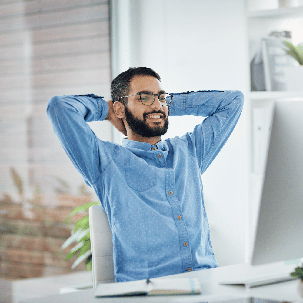 Person lehnt sich entspannt im Bürostuhl zurück und wirkt zufrieden mit ihrer Arbeit.